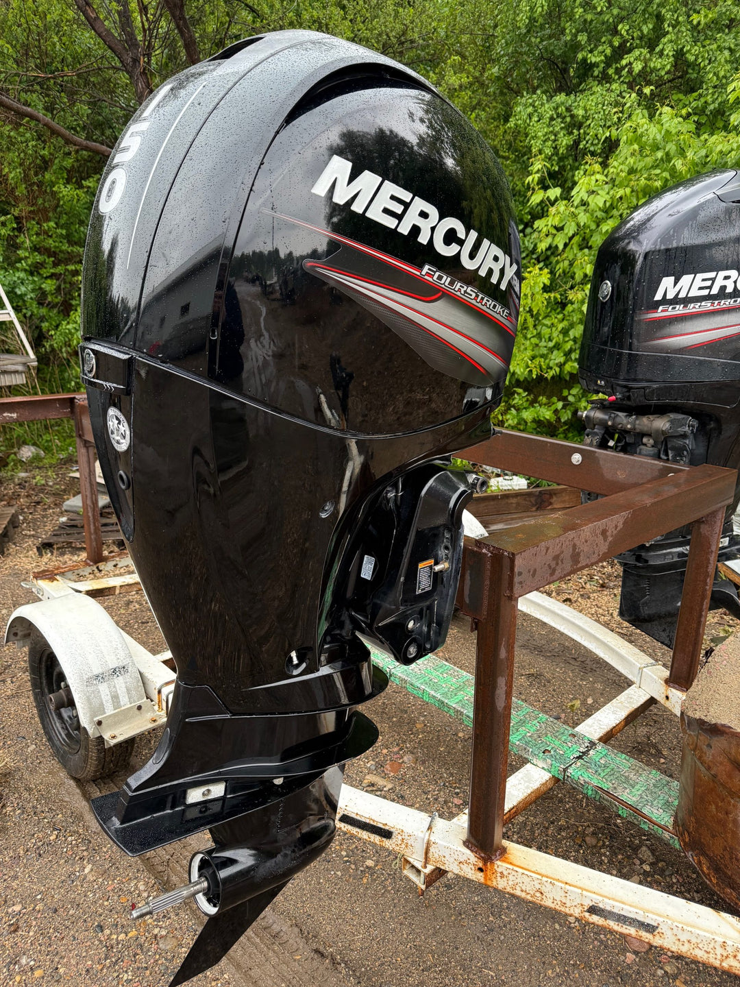 Black 150 horsepower Mercury outboard motor on a stand with trees in the background