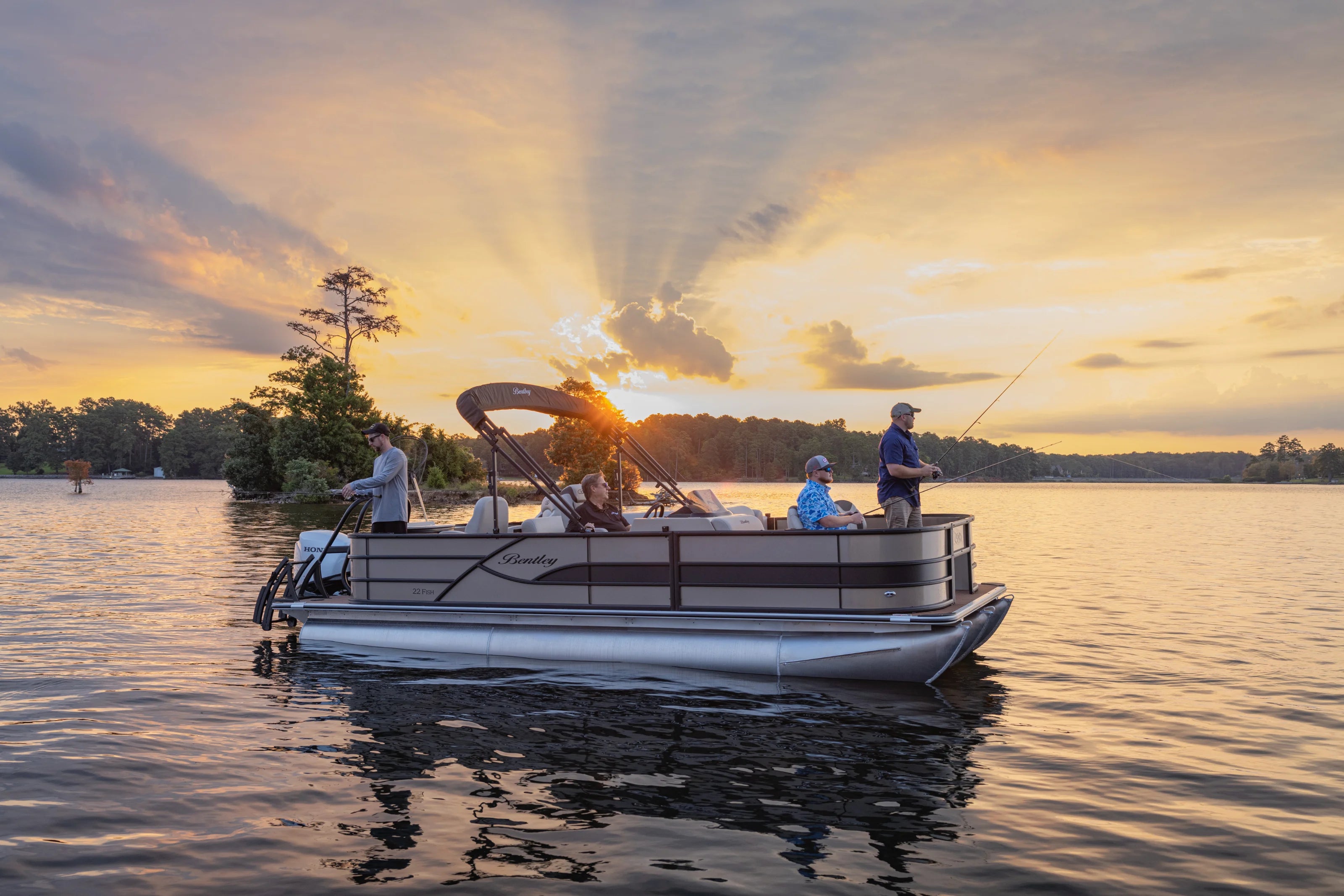 People on a Bentley tritoon boat at sunset on a lake