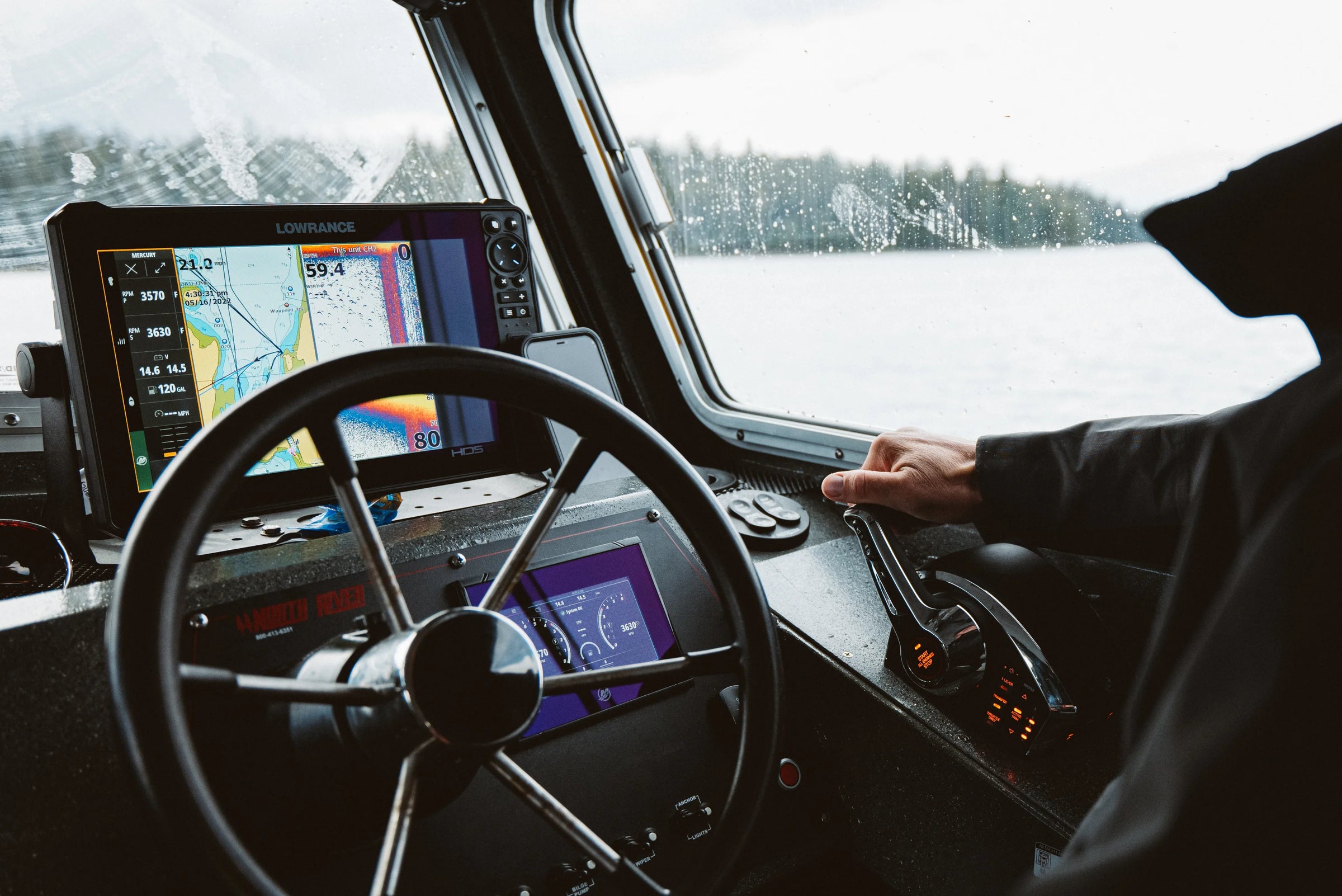 Person steering a boat with a navigation screen on a lake