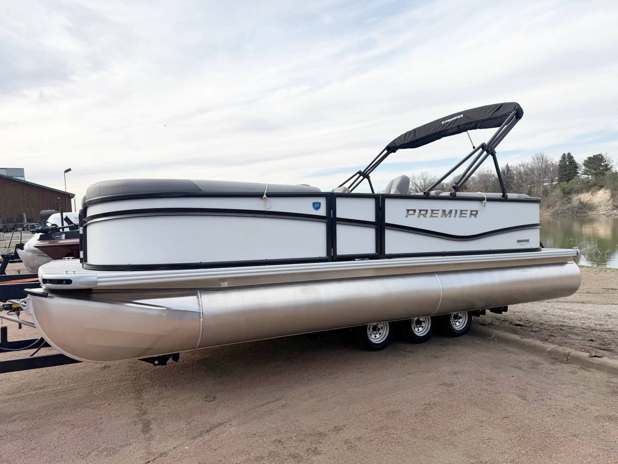 Premier Pontoon boat on a trailer with trees in the background