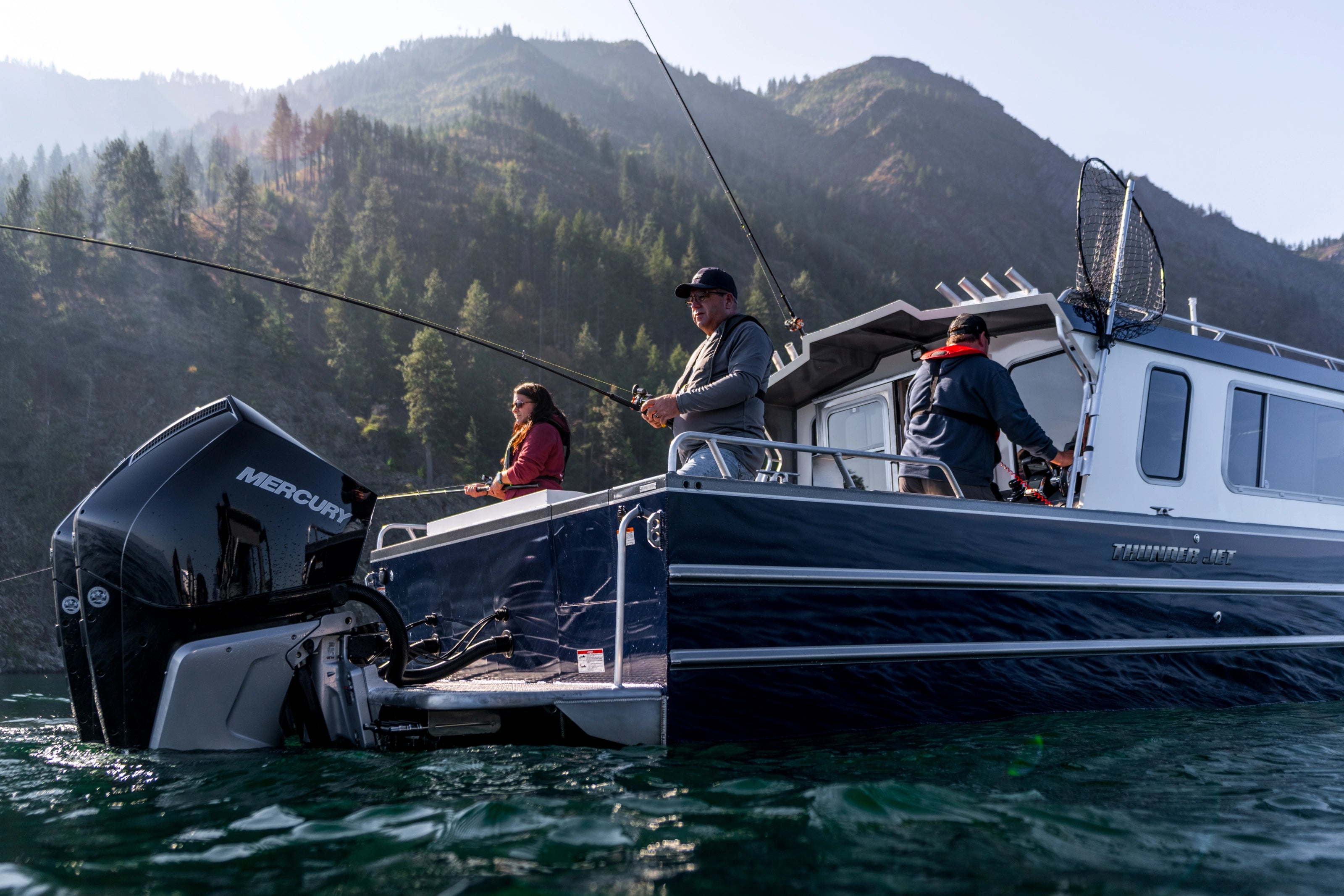 Thunder Jet Boat on water with people fishing, mountains in the background